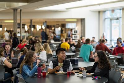Three students eating at a round table in the cafeteria.